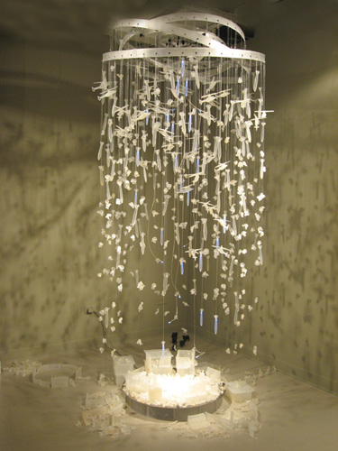 Teresa Diehl, The Last Lullaby, 2009, Installation<br/>Chandelier (Helicopters, missiles, Led Missiles, LED hanging lights and glycerine sheep) <br/>1 Metal plate with glycerine sheep, missiles, houses, walls <br/>